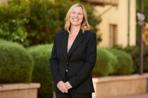 Photograph of Amander Clark, PhD wearing a black pant suit and smiling outside.