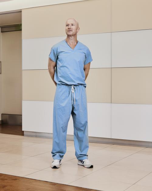 Dr. Jeffrey Veale, UCLA transplant surgeon, stands confidently in hospital scrubs and sneakers inside UCLA Health Center, leading research in delayed immune tolerance to eliminate lifelong immunosuppression in kidney transplant recipient