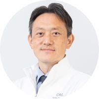 Professional headshot of a man in a white medical coat and tie