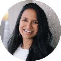 Headshot portrait of Aparna Bhaduri smiling with dark hair in a professional setting.