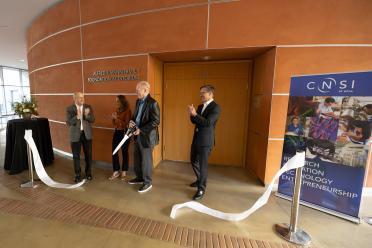 A group of people gather around a cut ribbon in a building 