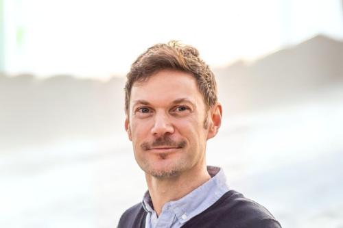 A smiling man photographed outdoors. 