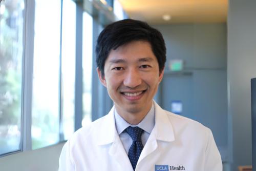 A doctor in a lab coat smiles for a photo. 