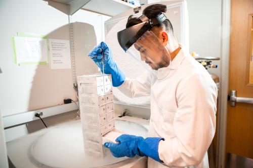 A scientist in PPE removes cells from a freezer