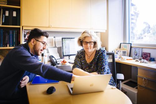 student and professor looking at laptop 