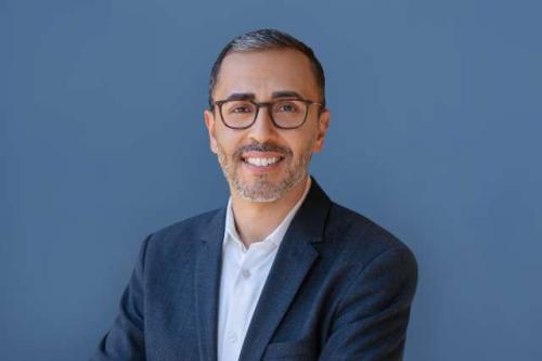 UCLA's Dr. Mina Sedrak smiles for a headshot wearing glasses and a light blue shirt with dark blue blazer.