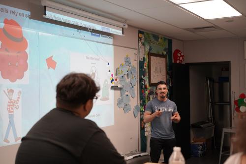 trainee chris ochoa leading a high school outreach session in front of a classroom