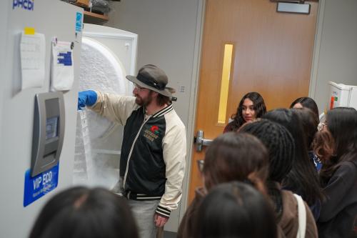 trainee dylan smock pulling stem cells out of a freezer as high school students look on