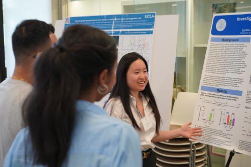 Students participate in the UCLA BSCRC's EOY CORE Resources Event, smiling and gesturing at a poster they're observing.
