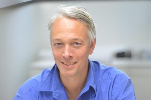 A headshot of Alexander Hoffman, Ph.D., who is pictured smiling and wearing a blue dress shirt.