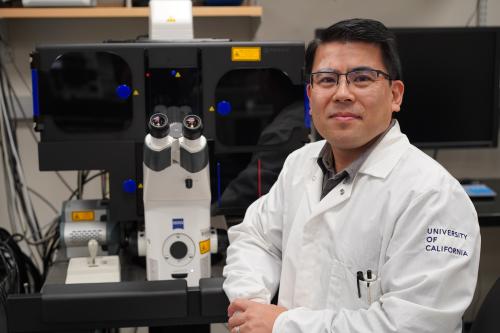 Ken Yamauchi standing next to microscope