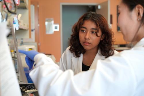 Two female researchers in the lab wearing lab coats