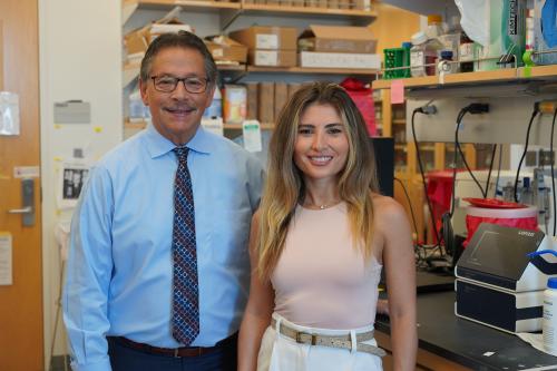 Scientist Donald Kohn on the left wearing a blue button down shirt and scientist Eva Segura on the right wearing a peach shirt; both are in the lab