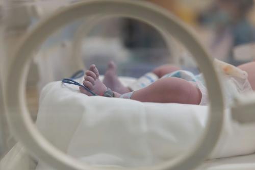 stock photo showing the legs of a newborn in a NICU with blue wires around the feet