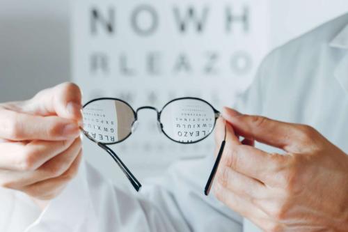Pair of hands holding eyeglasses.