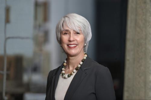 Headshot of Margaret Goodell in a dark blazer, light top and necklace against a faded background