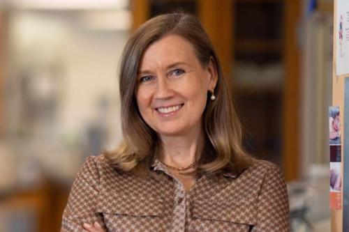 A researcher smiles into the camera inside a lab.