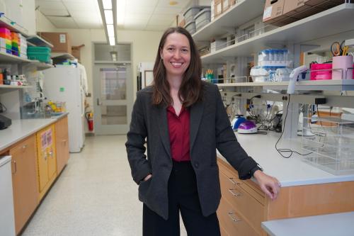 Headshot of Jennifer Chia in a research laboratory. She wears a dark gray blazer over a maroon blouse with black pants.