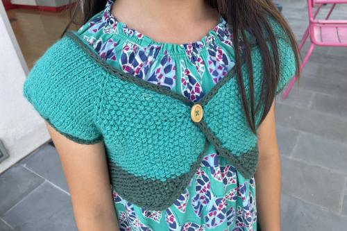 young girl wearing a green and blue knit shawl