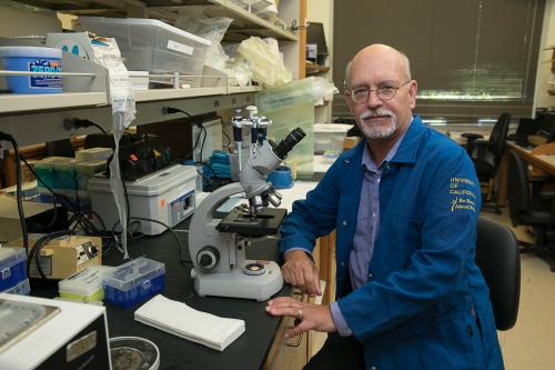 A researcher in a lab coat smiles in a UCLA lab