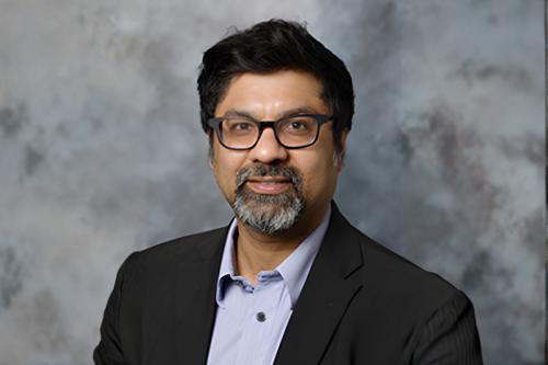Headshot of Sanjeev Kumar wearing glasses, a dark blazer and light blue button up