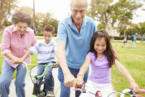 Two children ride their bikes with their grandparents.