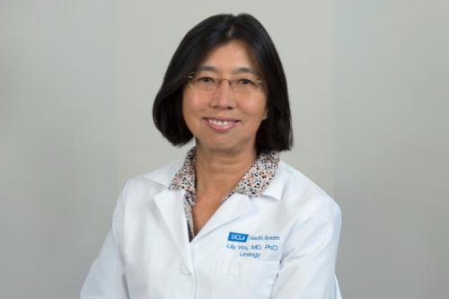 A doctor in a whitecoat smiles for a headshot.