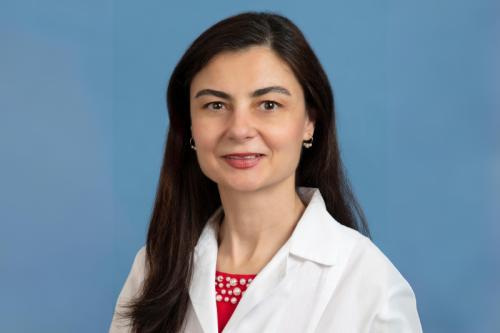 A woman in a labcoat smiles at the camera.