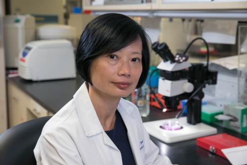 A researcher in a lab coat smiles in a UCLA lab
