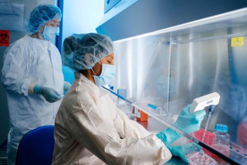 Two scientists wearing PPE work at a station in a UCLA cell therapy lab.