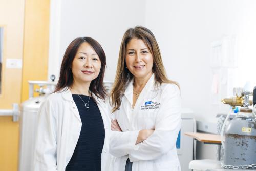 Image of Dr. Lili Yang (left) and Dr. Sanaz Memarzadeh (right) standing in a science laboratory.
