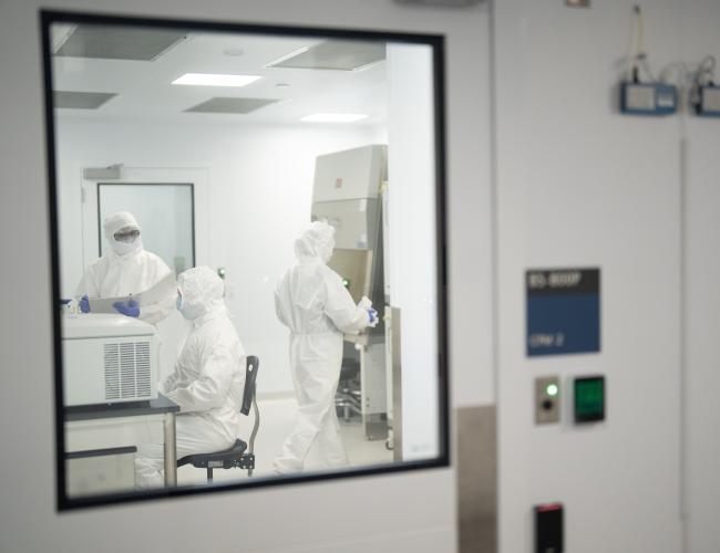 Three scientists clad in all-white "bunny" protective suits work inside the UCLA Center for Advanced Biotherapies.
