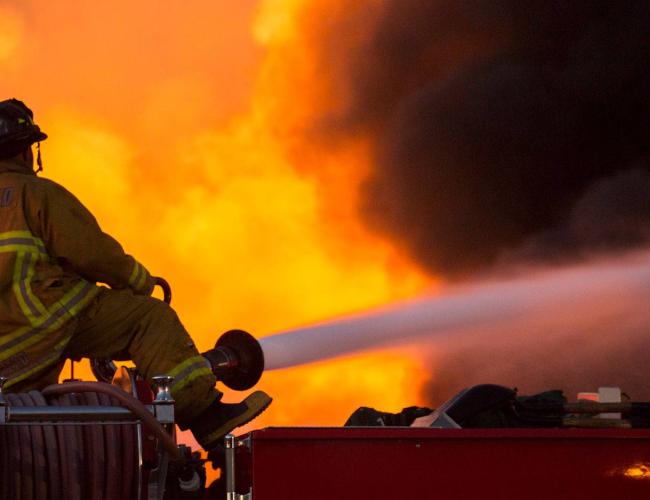 A firefighter can be observed hosing a blaze. 