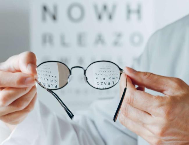 Pair of hands holding eyeglasses.