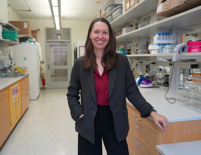 Headshot of Jennifer Chia in a research laboratory. She wears a dark gray blazer over a maroon blouse with black pants.