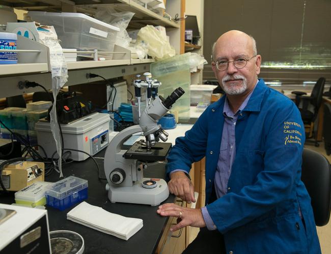 A researcher in a lab coat smiles in a UCLA lab