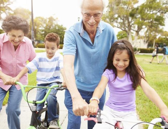 Two children ride their bikes with their grandparents.