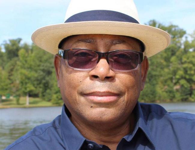 Close-up of Melvin Mann in dark blue shirt, sunglasses and straw fedora
