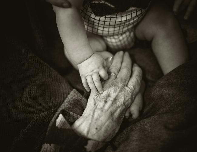 black and white photo of an infant holding an elderly woman's hand