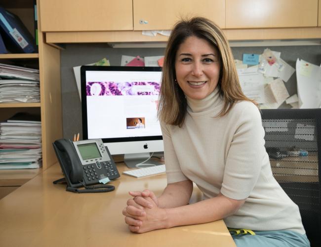 A UCLA researcher smiles in her office. 