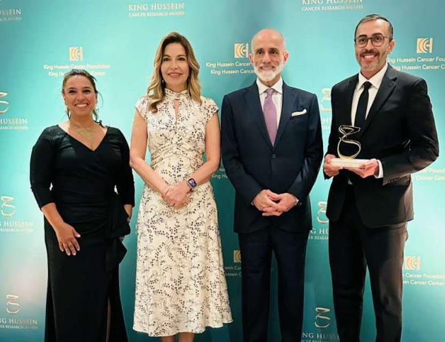 Four people pose at King Hussein Cancer Research Award ceremony; the person on the right holds an award trophy.