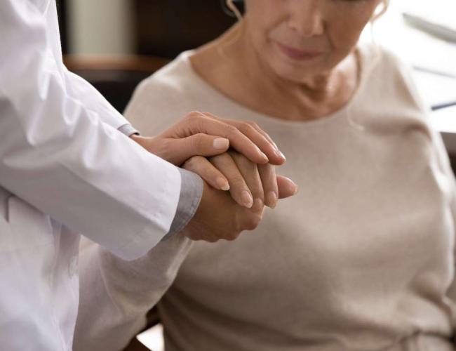 A doctor gently holds a patient's hand.
