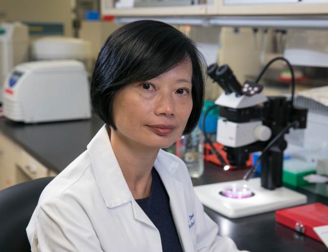 A researcher in a lab coat smiles in a UCLA lab