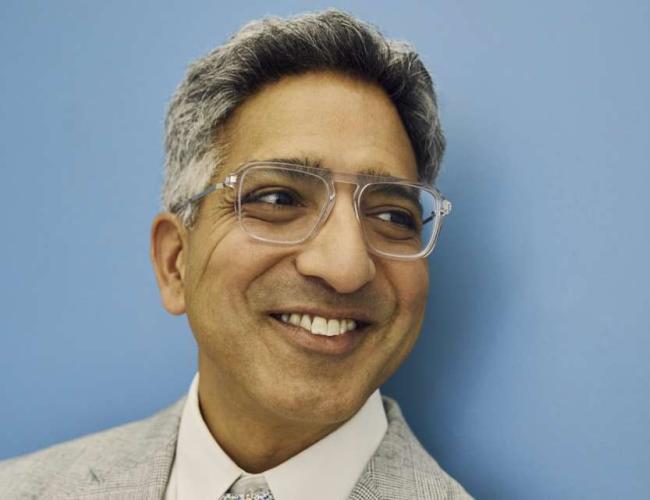A headshot of Dr. Manish Butte. He is smiling and wearing clear-framed glasses.