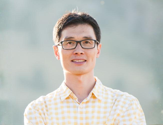 Headshot of Rui Yi in a light yellow checkered button up and glasses