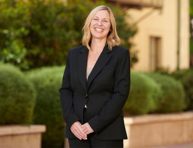 Photograph of Amander Clark, PhD wearing a black pant suit and smiling outside.