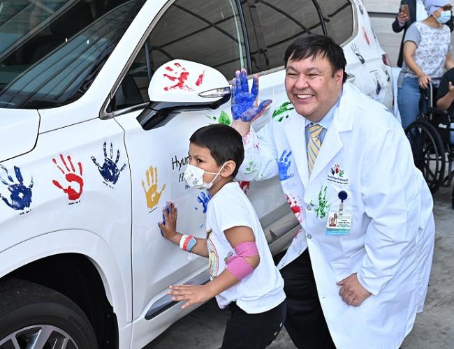 Dr. Steven Jonas and a patient at UCLA Mattel Children's Hospital put their handprints on a Hyundai during a celebration of Dr. Jonas receiving a $400,000 research grant. 