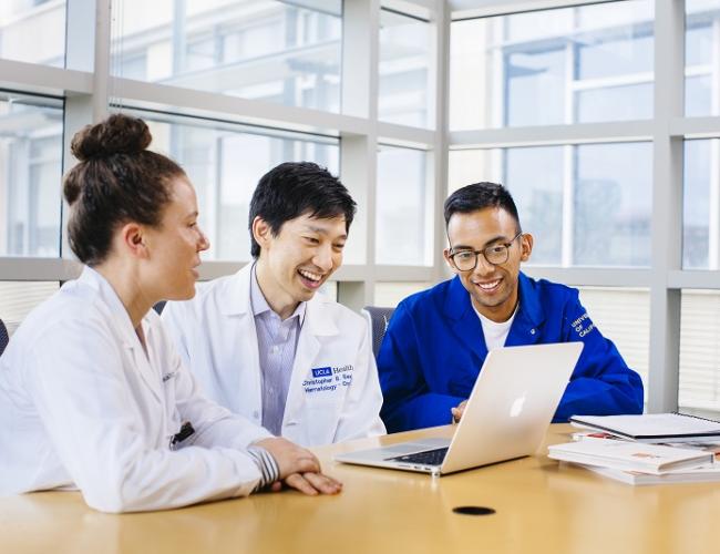 Three scientists gather around a computer.