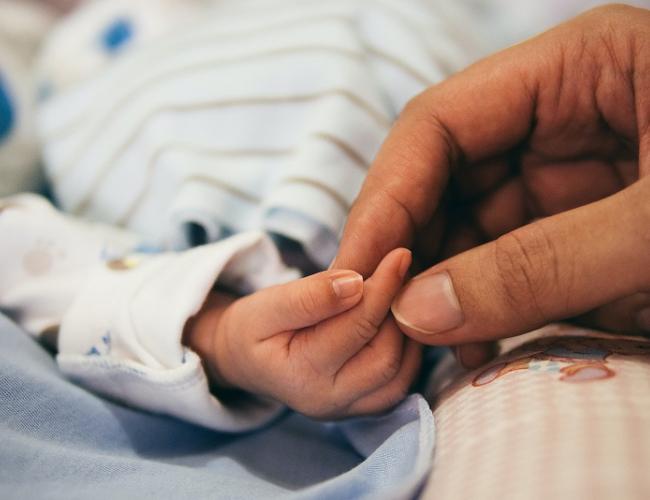 Parent holds tiny hand.