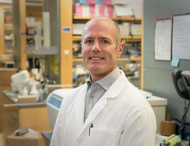 Headshot of S. Thomas Carmichael in a lab coat smiles in a UCLA lab